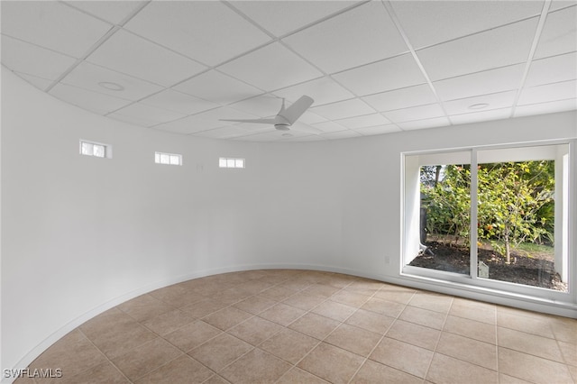 tiled empty room with ceiling fan and a drop ceiling