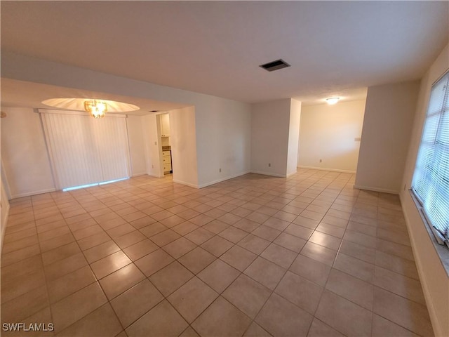 empty room with a notable chandelier and light tile patterned floors