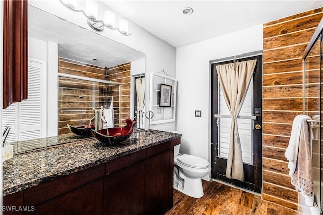 bathroom with vanity, hardwood / wood-style flooring, a shower with door, and toilet