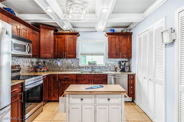 kitchen featuring a kitchen island, white cabinetry, sink, light tile patterned floors, and stainless steel appliances