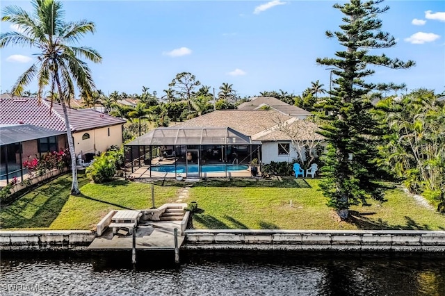 back of property with a water view, a lanai, and a lawn