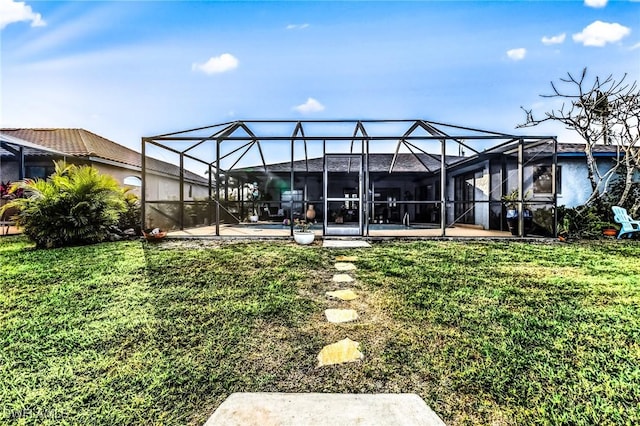 rear view of house with a patio area, glass enclosure, and a lawn