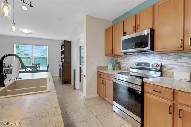 kitchen featuring hanging light fixtures, sink, stainless steel appliances, and light tile patterned flooring