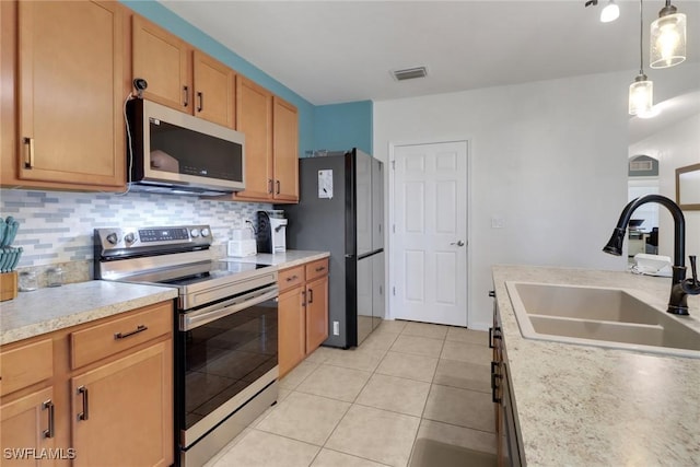 kitchen featuring backsplash, pendant lighting, light tile patterned flooring, sink, and appliances with stainless steel finishes