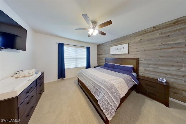 bedroom with ceiling fan, light colored carpet, and wooden walls