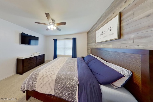 bedroom featuring ceiling fan, light colored carpet, and wood walls