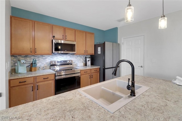 kitchen with appliances with stainless steel finishes, pendant lighting, tasteful backsplash, and sink