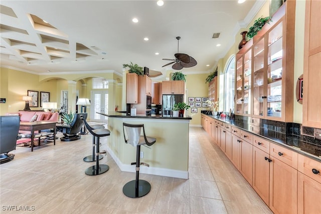 kitchen with ceiling fan, crown molding, coffered ceiling, a kitchen breakfast bar, and stainless steel fridge