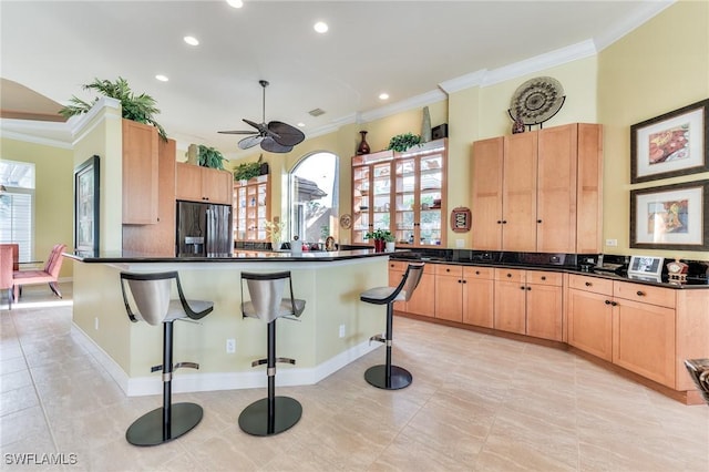 kitchen featuring ceiling fan, black refrigerator with ice dispenser, plenty of natural light, and a breakfast bar area