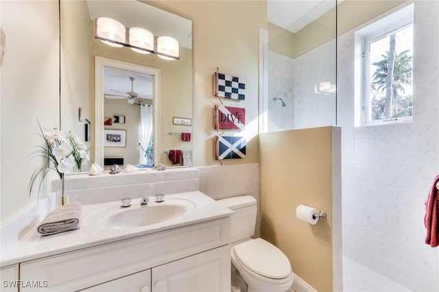 bathroom with ceiling fan, vanity, toilet, and tiled shower