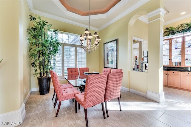 dining room featuring crown molding, light tile patterned floors, a tray ceiling, and a chandelier