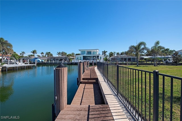 view of dock featuring a lawn and a water view