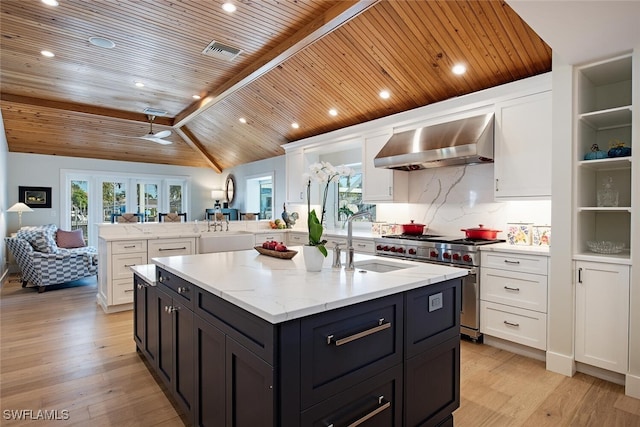 kitchen with range with two ovens, wall chimney exhaust hood, wooden ceiling, a sink, and white cabinetry