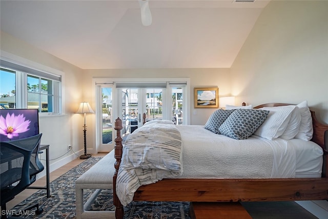 bedroom featuring access to exterior, lofted ceiling, wood finished floors, and baseboards