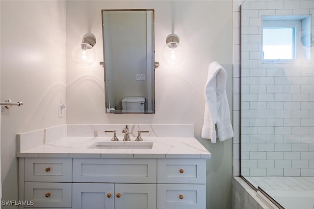 bathroom with a tile shower, vanity, and toilet