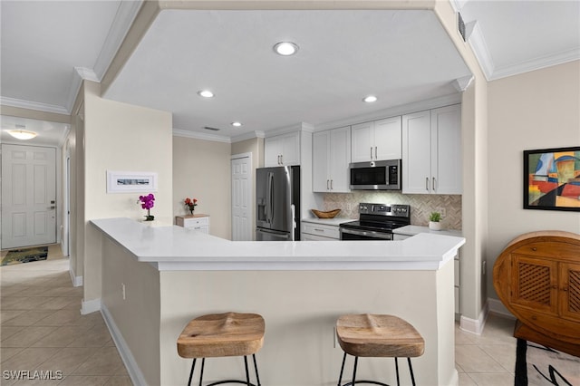 kitchen with kitchen peninsula, stainless steel appliances, a kitchen bar, and white cabinetry