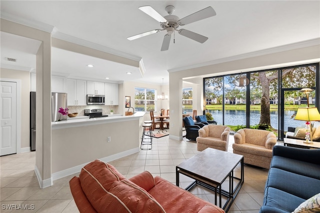 tiled living room with ceiling fan with notable chandelier, a healthy amount of sunlight, a water view, and crown molding