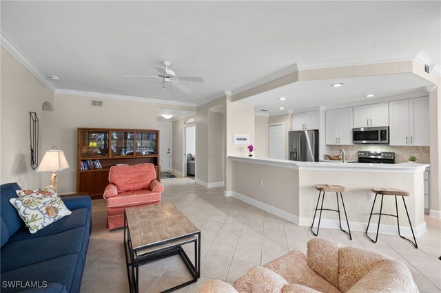 tiled living room with ceiling fan, sink, and crown molding