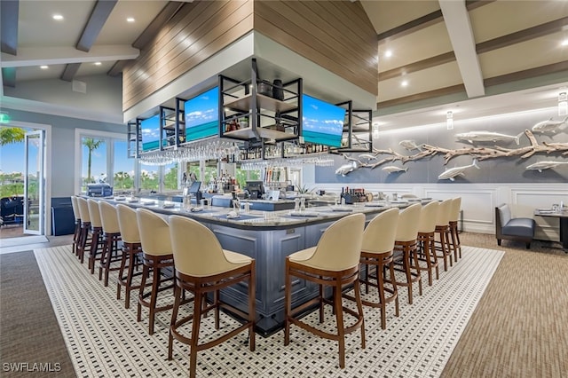 bar featuring beam ceiling, light colored carpet, and a high ceiling