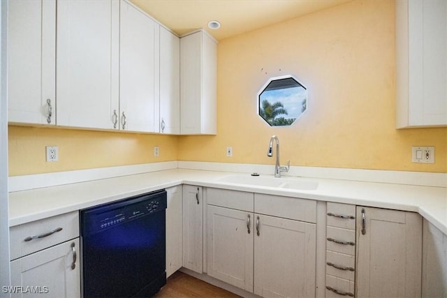 kitchen with hardwood / wood-style flooring, dishwasher, white cabinets, and sink