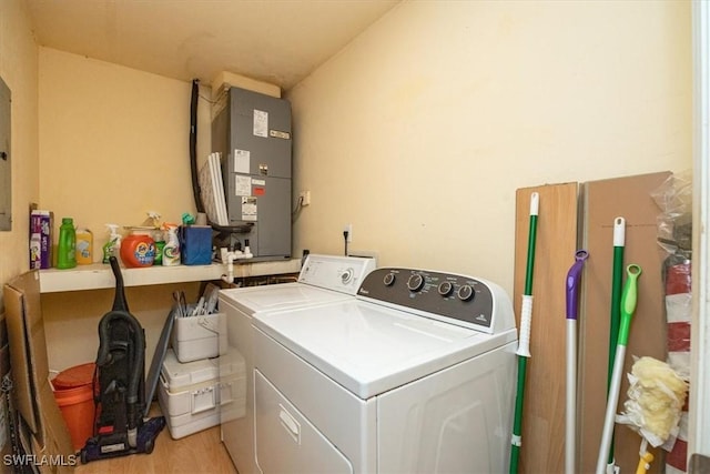 washroom with washer and dryer, heating unit, and light wood-type flooring