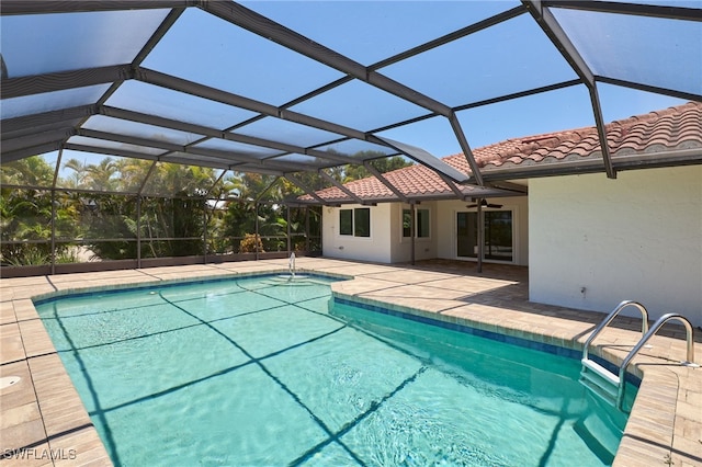 view of swimming pool featuring glass enclosure, a patio area, and ceiling fan