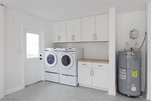 washroom with electric water heater, washer and dryer, and cabinets