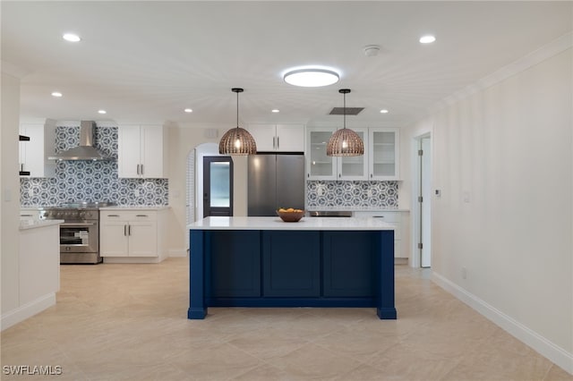 kitchen with decorative backsplash, white cabinetry, hanging light fixtures, appliances with stainless steel finishes, and wall chimney exhaust hood