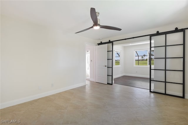 unfurnished room with ceiling fan and a barn door