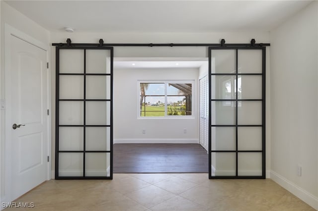 spare room with a barn door and light tile patterned flooring