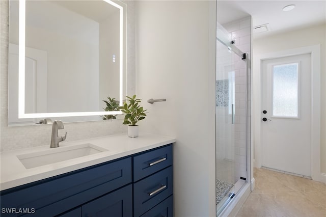 bathroom featuring a shower with shower door and vanity