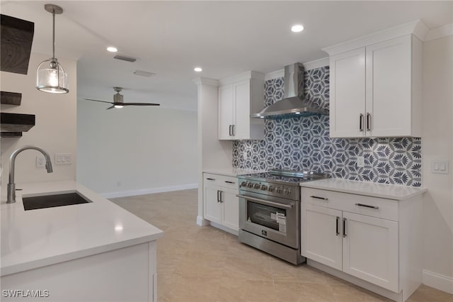 kitchen with sink, wall chimney range hood, white cabinets, and high end stove