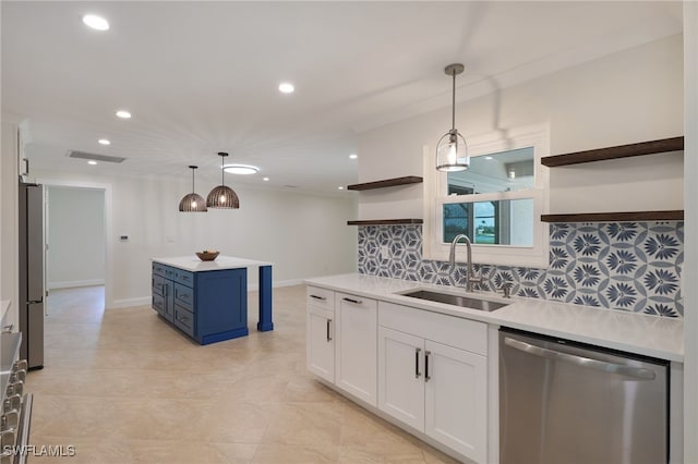 kitchen featuring decorative light fixtures, sink, stainless steel appliances, and white cabinetry