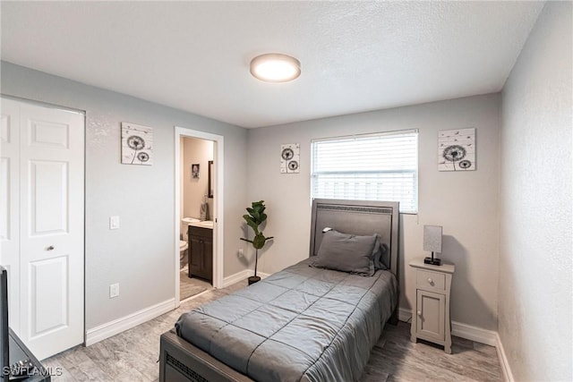 bedroom featuring ensuite bathroom, light hardwood / wood-style floors, a closet, and a textured ceiling