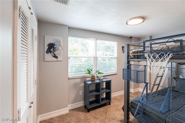 tiled bedroom featuring multiple windows and a textured ceiling