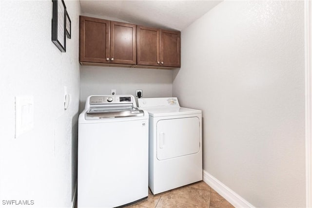 washroom featuring cabinets, light tile patterned floors, washing machine and clothes dryer, and a textured ceiling