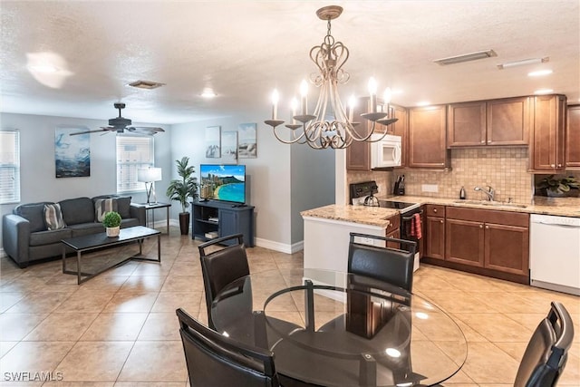 dining space featuring light tile patterned flooring, ceiling fan with notable chandelier, sink, and a textured ceiling