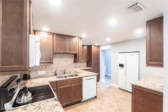 kitchen featuring sink, white appliances, light tile patterned floors, light stone countertops, and decorative backsplash