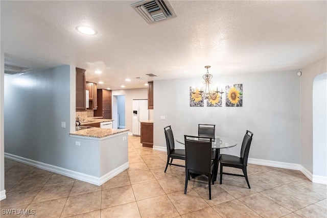 dining space featuring light tile patterned flooring, a chandelier, and a textured ceiling