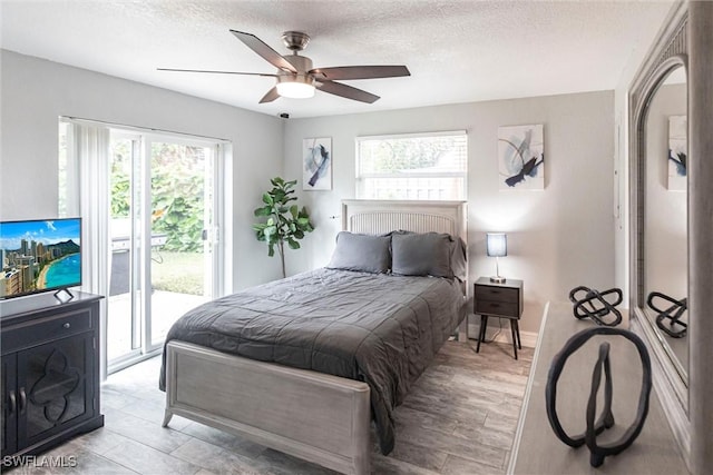 bedroom featuring access to exterior, a textured ceiling, light hardwood / wood-style floors, and ceiling fan