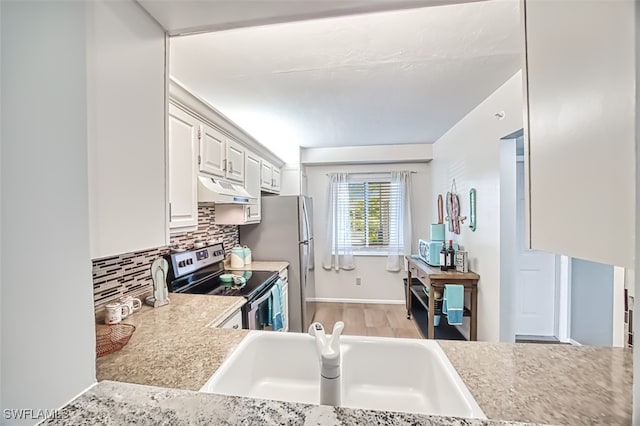 kitchen with appliances with stainless steel finishes, white cabinetry, sink, backsplash, and light hardwood / wood-style flooring