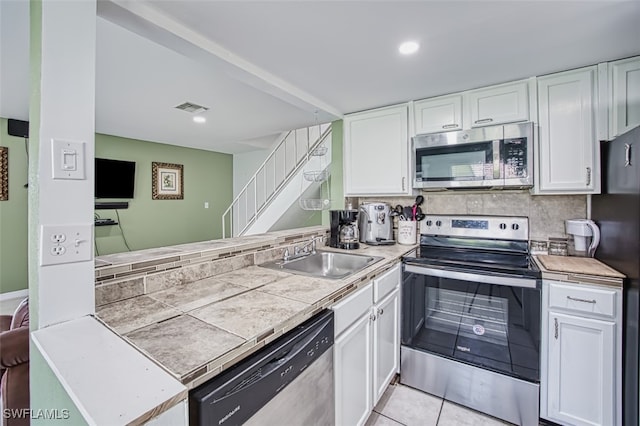 kitchen with light tile patterned floors, stainless steel appliances, white cabinetry, and sink