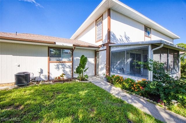 exterior space with a front lawn, a sunroom, and central AC unit