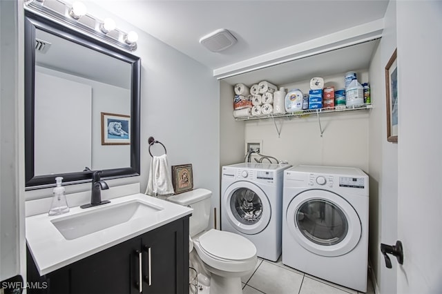 clothes washing area with light tile patterned floors, washer and dryer, and sink