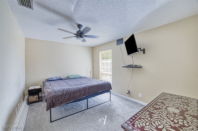 bedroom featuring light carpet, ceiling fan, and a textured ceiling