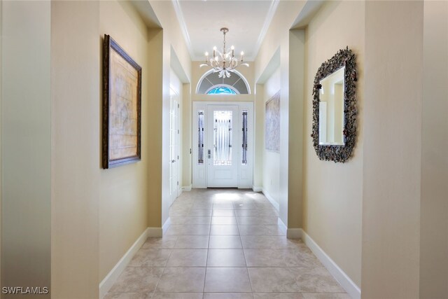 tiled entrance foyer with an inviting chandelier and crown molding