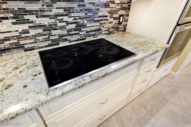 details featuring black electric cooktop, decorative backsplash, oven, and light stone counters