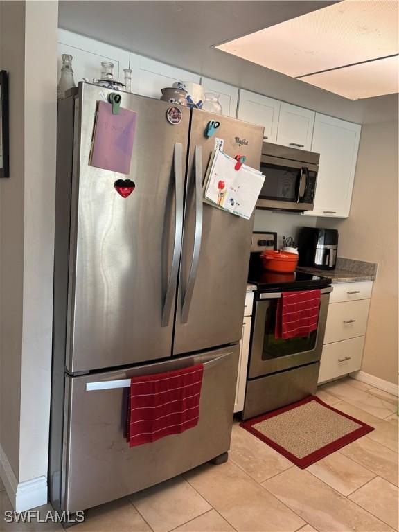 kitchen with white cabinets, appliances with stainless steel finishes, and light tile patterned floors