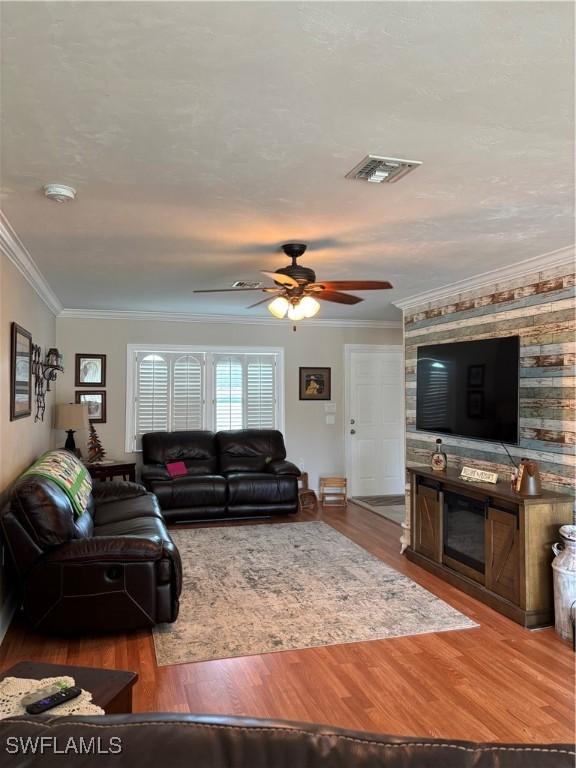 living room with ceiling fan, crown molding, and wood-type flooring