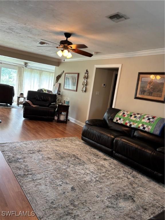 living room with ceiling fan, ornamental molding, and light hardwood / wood-style flooring